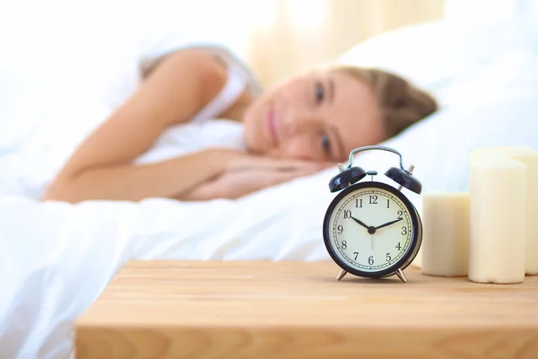 Jeune femme endormie et réveil dans la chambre à coucher à la maison — Photo