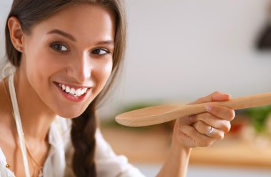 Mutfakta ahşap kaşıkla yemek pişiren kadın