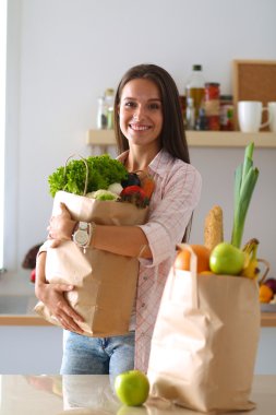 Elinde sebzeli alışveriş torbası tutan genç bir kadın.