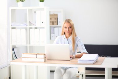 Ofiste dizüstü bilgisayarı olan çekici bir iş kadını.