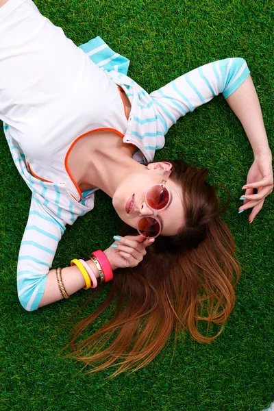 Mooie jonge vrouw liggend op groen gras — Stockfoto