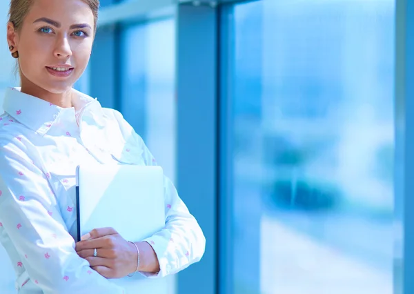 Businesswoman standing against office window holding documents in hand — Stock Photo, Image