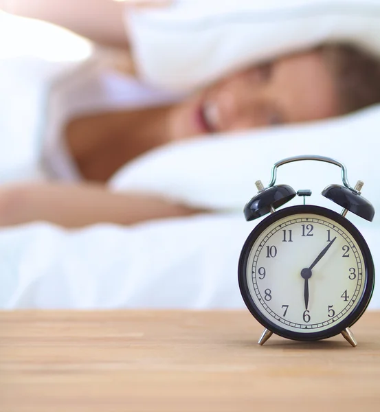 Young sleeping woman and alarm clock in bedroom at home — Stock Photo, Image