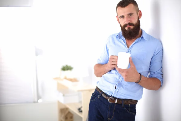 Jonge man permanent in de buurt van muur en houden kopje koffie — Stockfoto