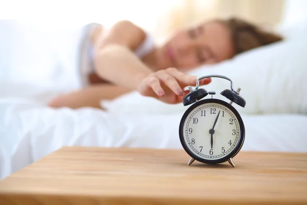 Joven mujer dormida y despertador en el dormitorio en casa — Foto de Stock