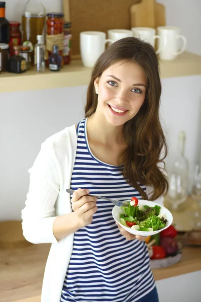 Młoda kobieta jedzenie sałatka i trzymając mix sałat — Zdjęcie stockowe