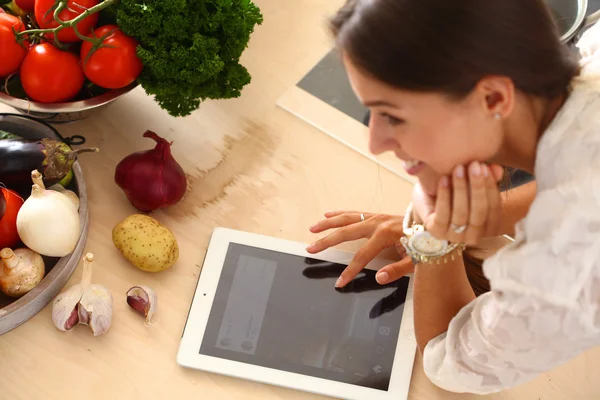 Mujer joven usando una tableta para cocinar en su cocina — Foto de Stock