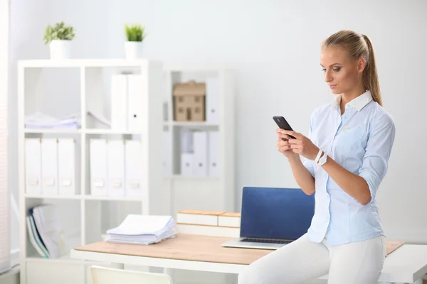 Jonge zakenvrouw permanent in kantoor praten over haar mobiele telefoon — Stockfoto