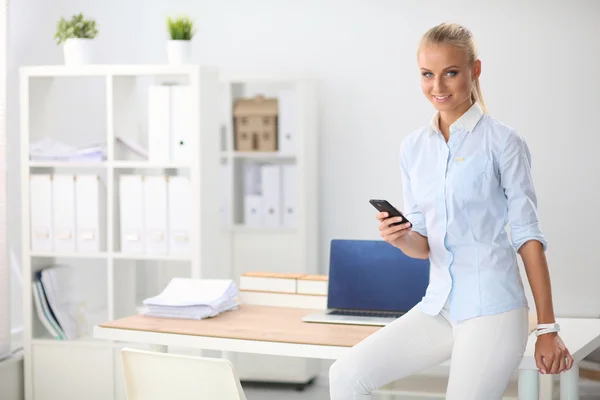 Young business woman standing in office talking on her mobile phone — Stock Photo, Image