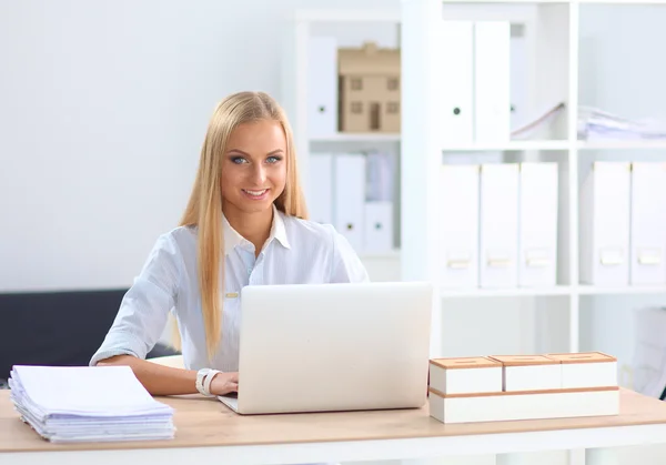 Attractive businesswoman sitting on a desk with laptop in the office — Stock Photo, Image