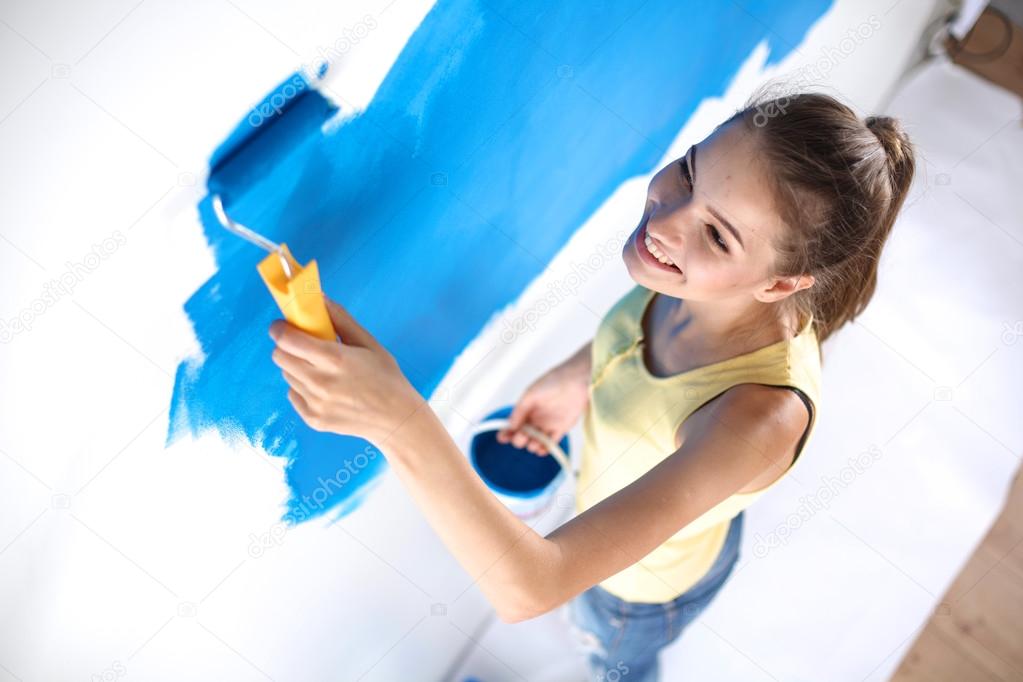 Happy beautiful young woman doing wall painting