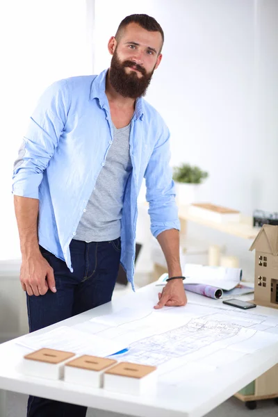 Portrait of male designer in hat with blueprints at desk — Stock Photo, Image