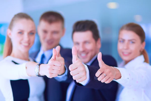 Feliz equipo de negocios mostrando pulgares hacia arriba en la oficina — Foto de Stock