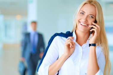 İş kadını ofis penceresinin önünde cep telefonuyla konuşuyor