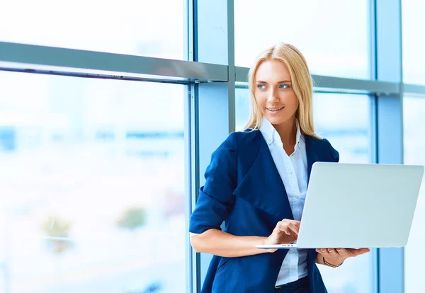 Podnikatelka, stojící proti úřadu okno drží notebook — Stock fotografie