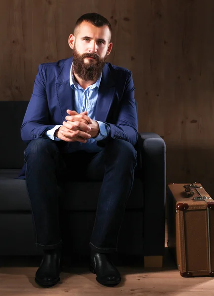 Businessman sitting the sofa in office lobby, isolated on dark background — Stock Photo, Image