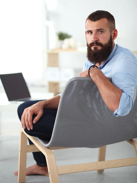 Young businessman sitting on chair with book in office — Stock Photo, Image