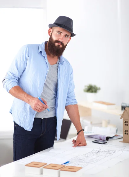 Portret van mannelijke ontwerper in hoed met blauwdrukken aan balie — Stockfoto