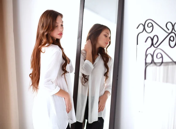 Jovem mulher olhando-se reflexão no espelho em casa — Fotografia de Stock