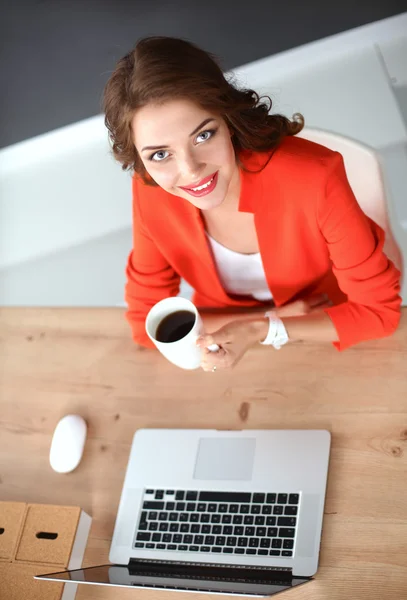 迷人的女人坐在办公室的办公桌前，与笔记本电脑一起工作 — 图库照片