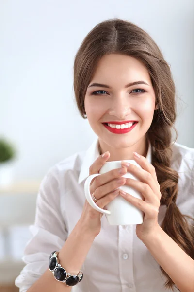 Attractive businesswoman sitting  on desk in the office — Stock Photo, Image