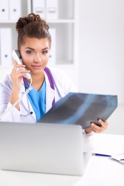 Masada oturan genç bayan doktor röntgen üzerinde çalışıyor.