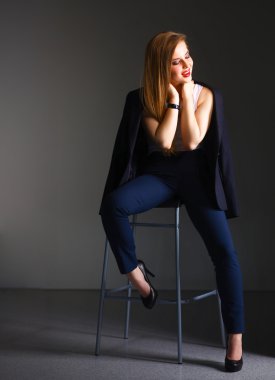 Genç bir kadın sandalyede oturuyor.