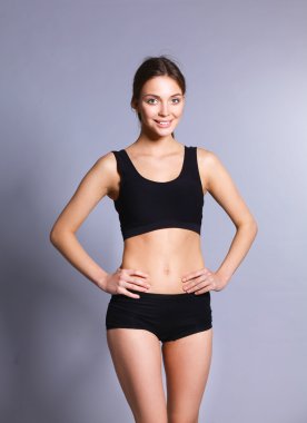 Gri arka plan üzerinde duran genç kadın