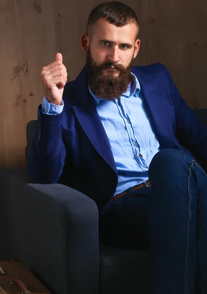 Affärsman som sitter i soffan i kontoret lobbyn, isolerad på mörk bakgrund — Stockfoto