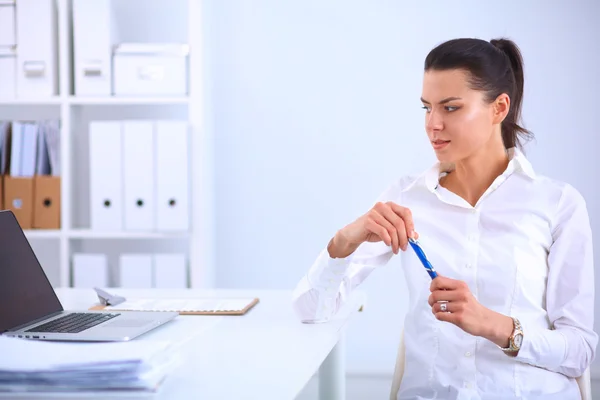 Atractiva mujer de negocios sentada en un escritorio con portátil en la oficina — Foto de Stock