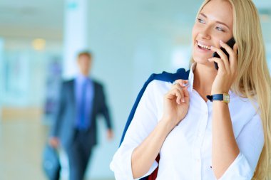 İş kadını ofis penceresinin önünde cep telefonuyla konuşuyor