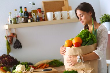 Elinde sebzeli alışveriş torbası tutan genç bir kadın.