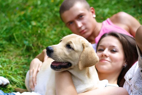 Una pareja sonriente con su perro al aire libre — Foto de Stock
