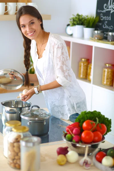 Молодая женщина, стоящая у плиты на кухне — стоковое фото