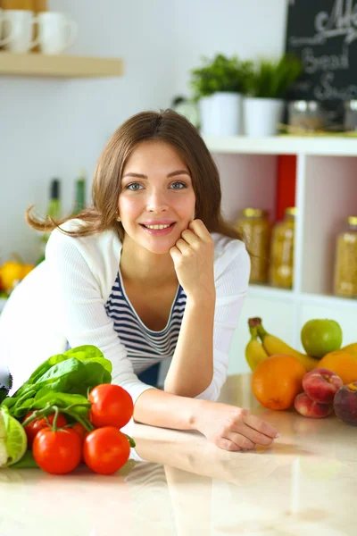 Jonge vrouw zit in de buurt van bureau in de keuken — Stockfoto