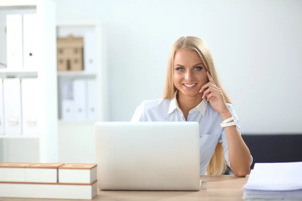 Attractive businesswoman sitting on a desk with laptop in the office — Stock Photo, Image