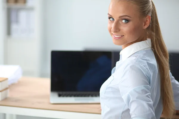 Atractiva mujer de negocios sentada en un escritorio con portátil en la oficina — Foto de Stock