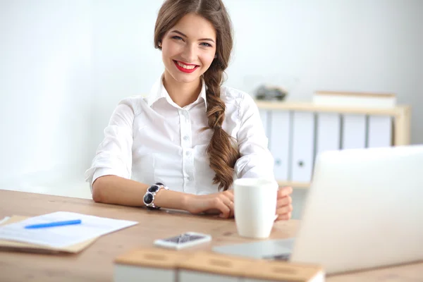 Atraktivní podnikatelka sedící na stole v kanceláři — Stock fotografie