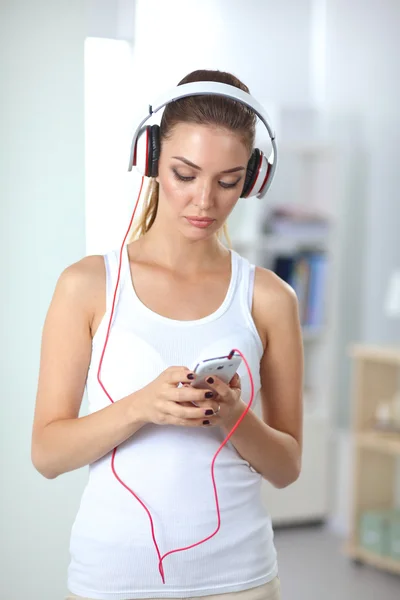 Женщина с наушниками слушает музыку стоя дома — стоковое фото