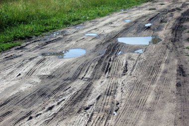 Tekerlek izlerinin ve su birikintilerinin olduğu kötü toprak yol. Düşük kaliteli yollar kavramı.