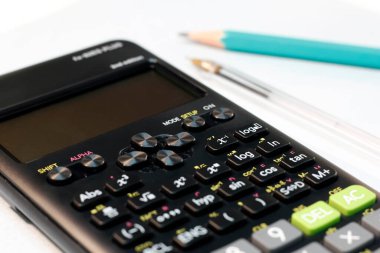 Işık arkaplanındaki bilimsel hesap makinesi, kalem ve kalem..