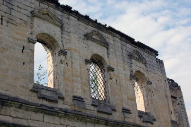 Penceresiz, gökyüzüne karşı çatısı olan eski bir taş binanın cephesi..