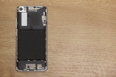 Arka kapağı açık akıllı telefon masanın üzerinde. Aygıt onarımı kavramı.