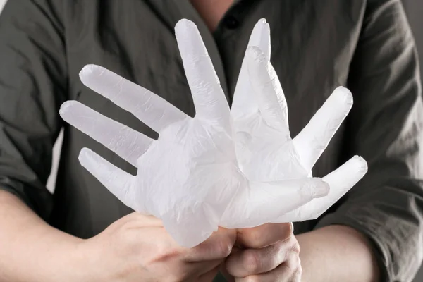 Hands holding disposable vinyl gloves filled with air. New normal reality. Infection prevention during lockdown. Close up cropped image.