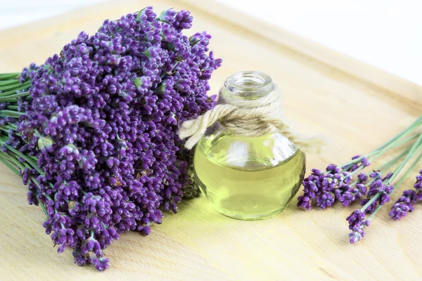 Fresh lavender flowers and oil on wooden background — Stock Photo, Image