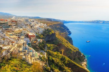 Santorini kasabası Thera Fira, Yunanistan panoramasında beyaz evler, yüksek volkanik kayalar ve gün batımında mavi deniz
