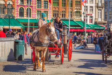 Bruges, Belçika - 10 Nisan 2016: Belçika 'nın popüler tatil beldesi Brugge' de pazar meydanında at arabası