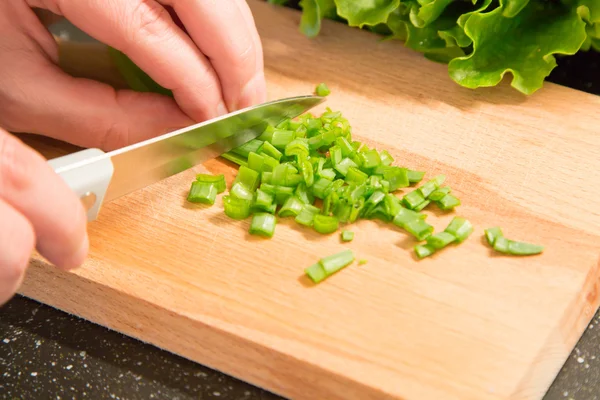 ตัดหัวหอมสีเขียวและมือด้วยมีด — ภาพถ่ายสต็อก