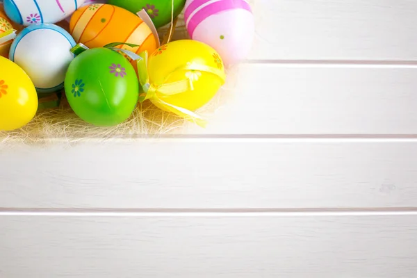 Green grass box with Easter eggs on white wooden board background — Stock Photo, Image