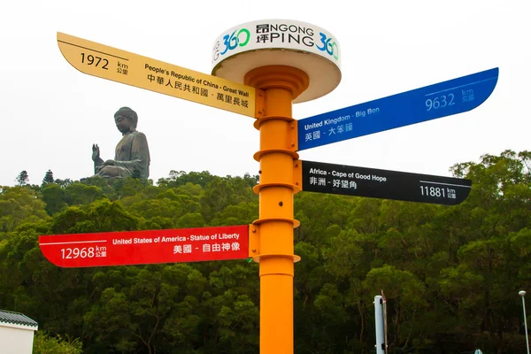 The signpost to different world destinations and Tian Tan Giant Buddha, Lantau Island in Hong Kong — Stock Photo, Image